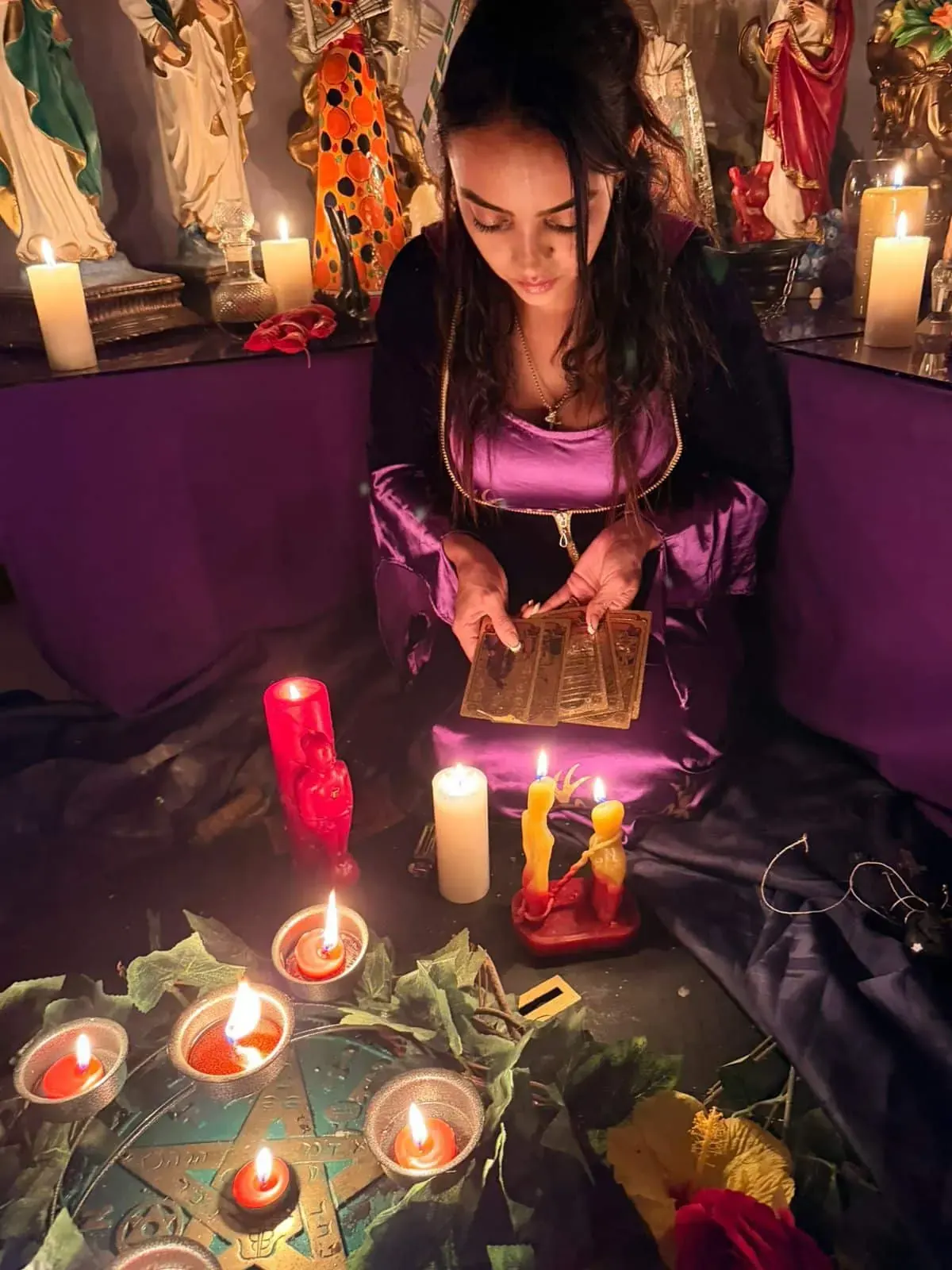 La Maestra Sara lee las cartas del tarot frente al altar, rodeada de velas