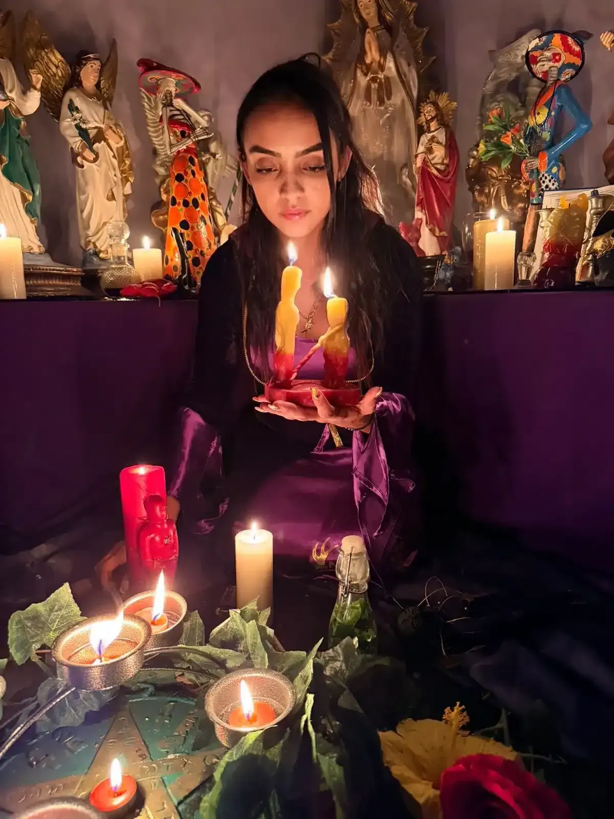 La Maestra Sara sostiene un plato con velas amarillas encendidas frente al altar