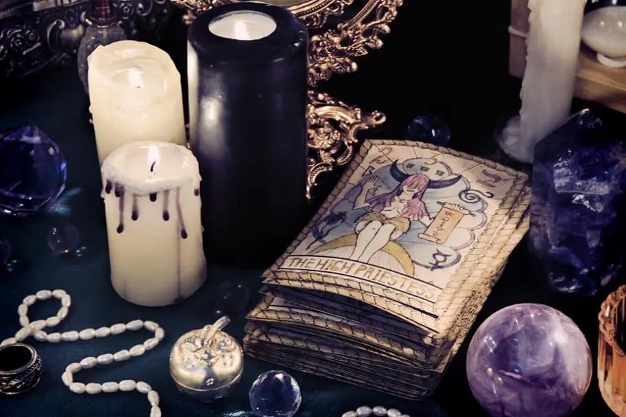 Velas blancas y negras, cartas antiguas, cristales y una esfera de amatista sobre una mesa